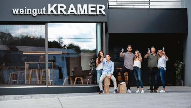 Group of people in front of a winery with glasses in their hands.