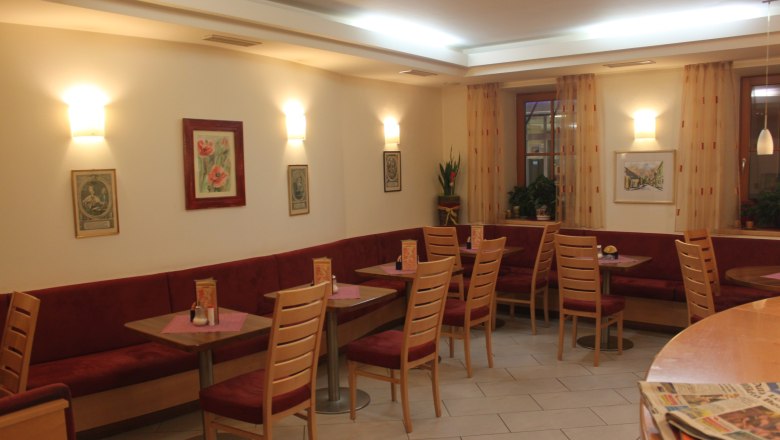 Interior view of a cozy café with red benches and wooden tables.