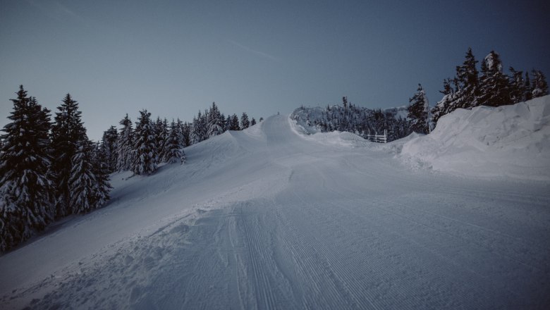 Snow-covered ski slope in the Unterberg ski area at dusk.