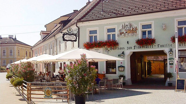 Exterior view of a traditional inn with terrace and parasols.