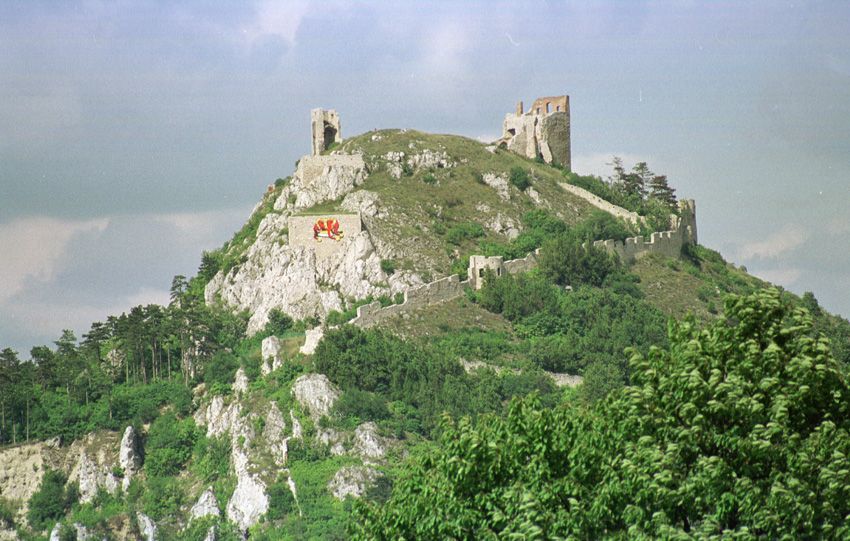 Ruins of the Staatz castle ruins on a hill with green vegetation.