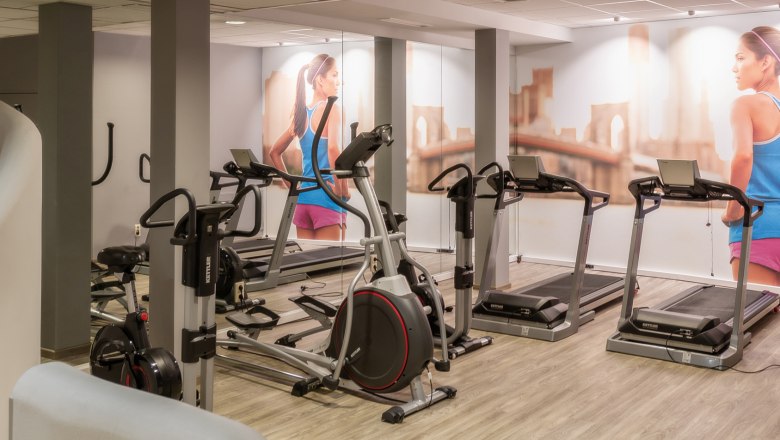 Fitness room with treadmills and fitness equipment, mural of a woman running.