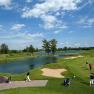 Golf course with water hazards and players under a blue sky.