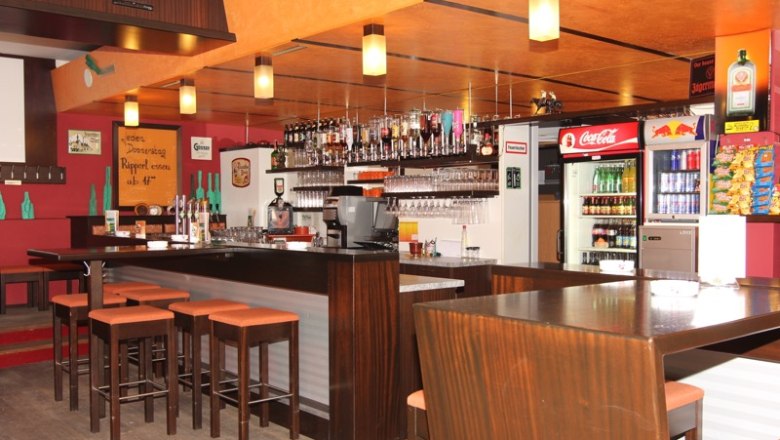 Interior view of a bar with wooden furniture, bar stools and drinks.