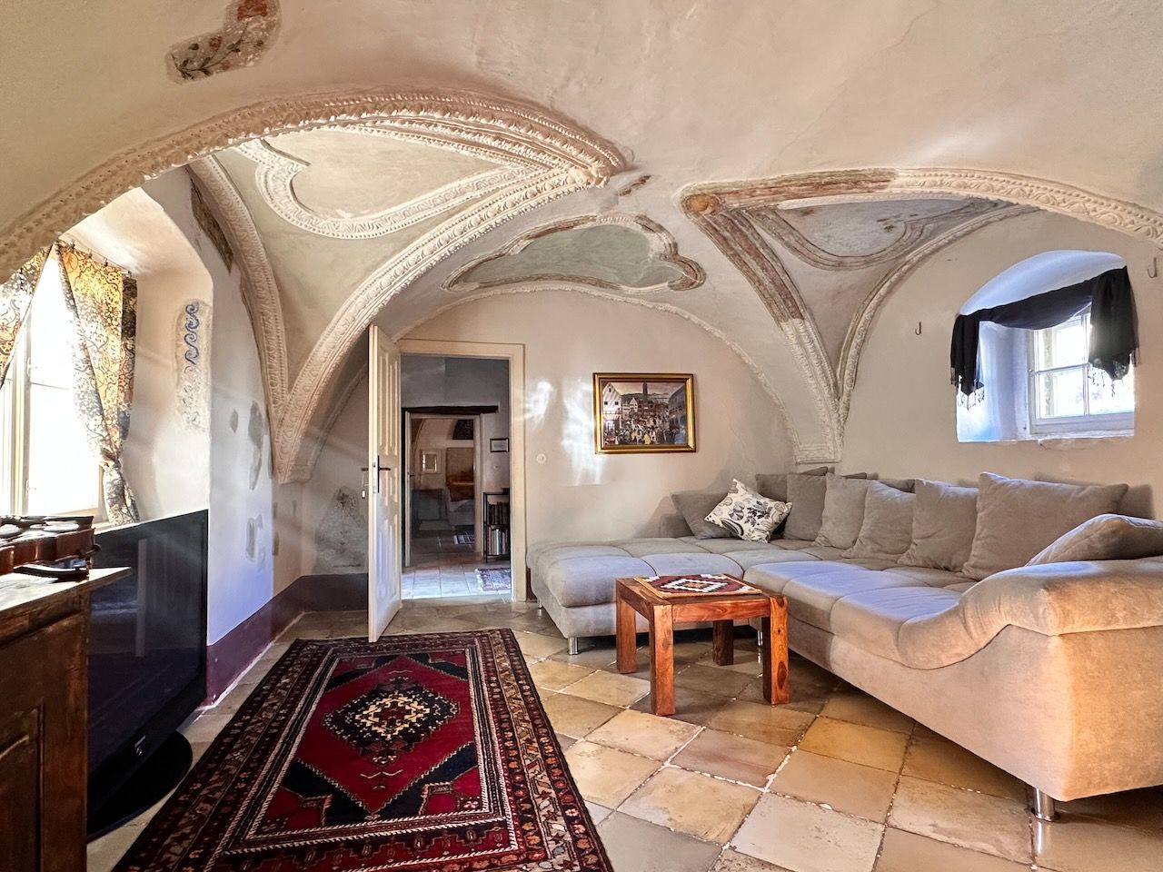 Historic room with vaulted ceiling, modern couch and carpet.