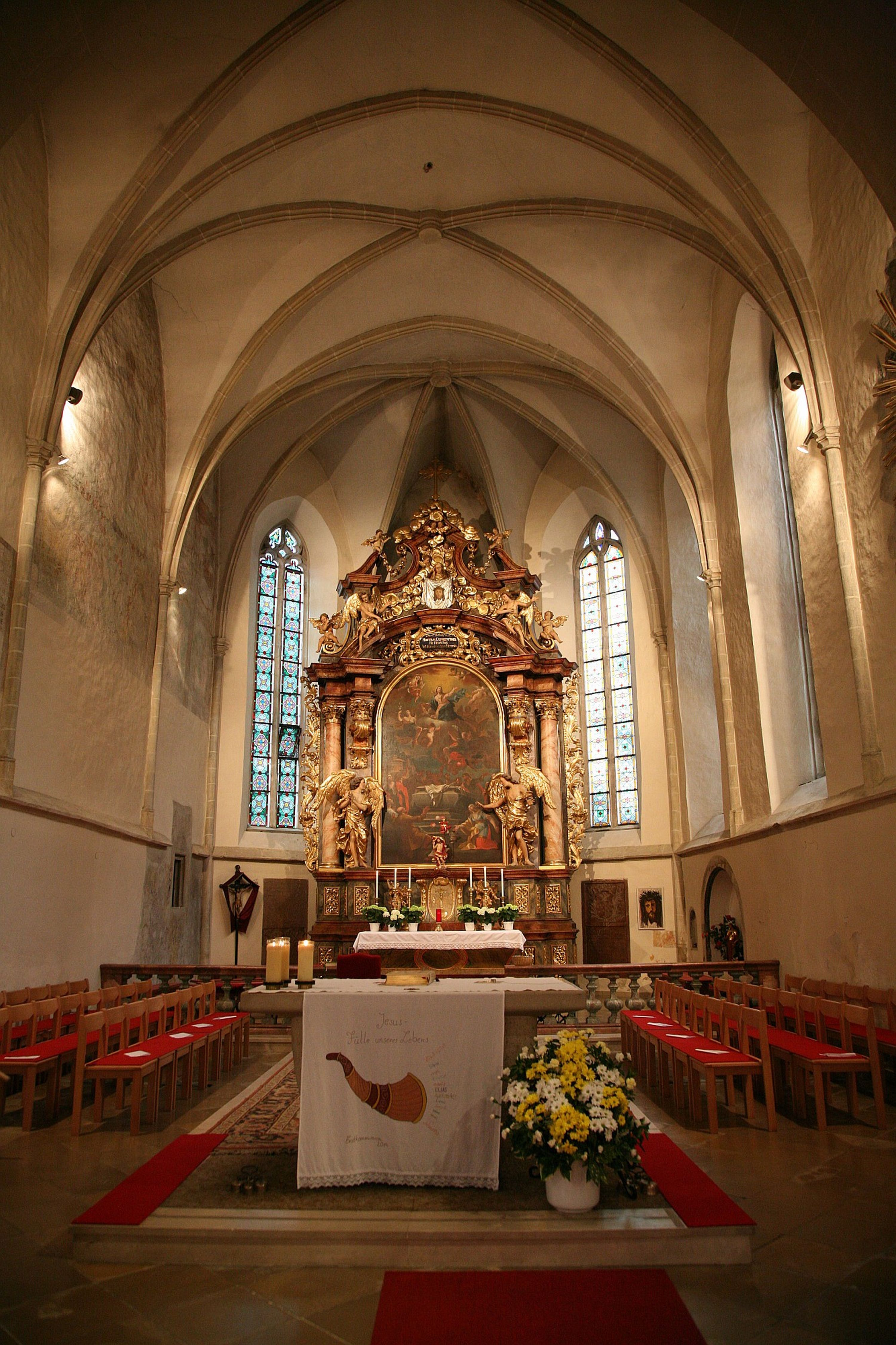 Interior view of a church with altar and stained glass windows.