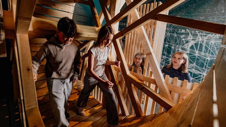 Children explore a wooden structure in a museum.