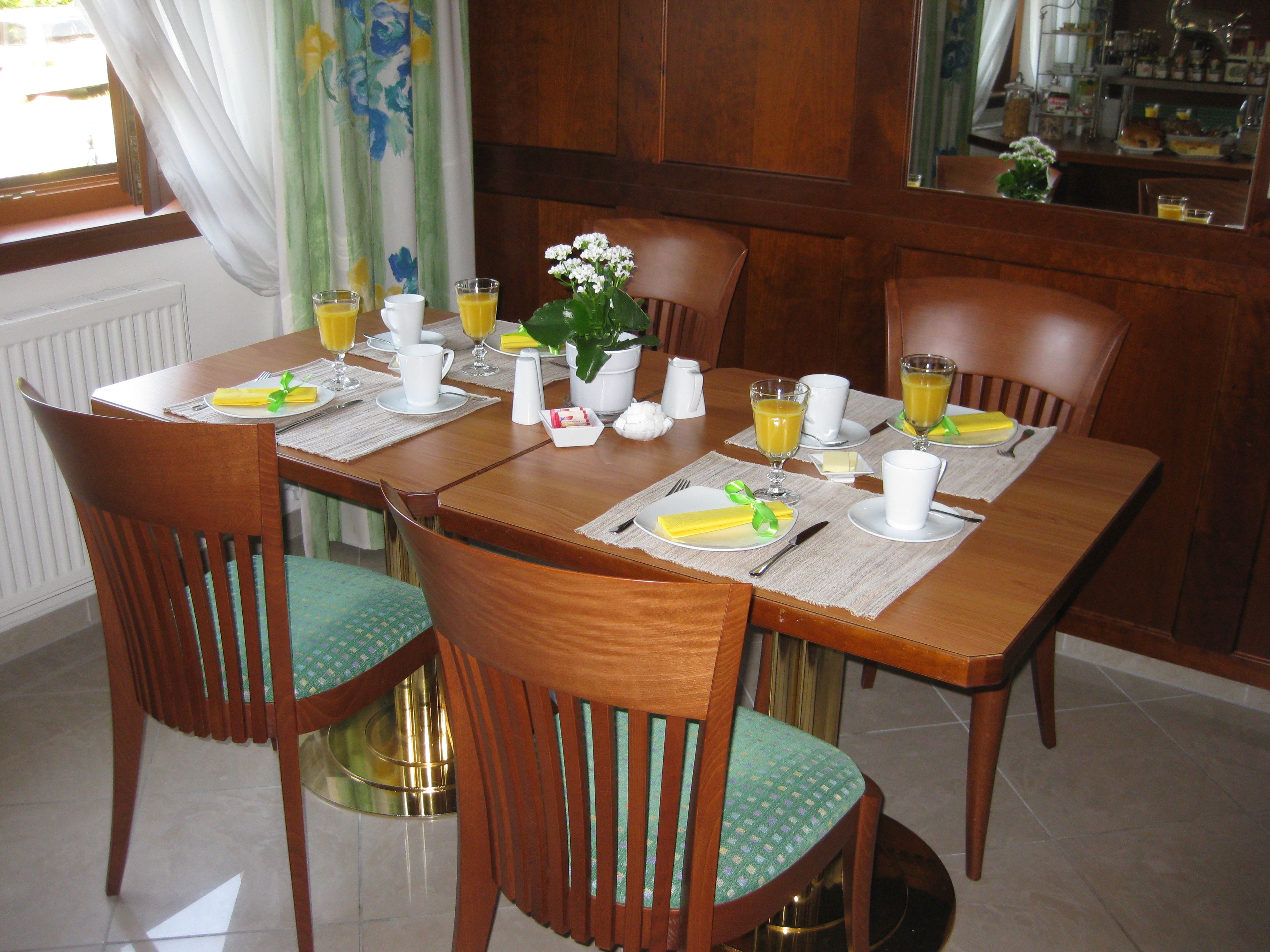 A laid breakfast table with juice, cups and flowers in a cozy room.