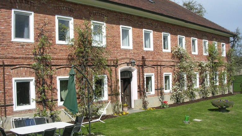 Brick building with garden furniture and parasol on lawn.