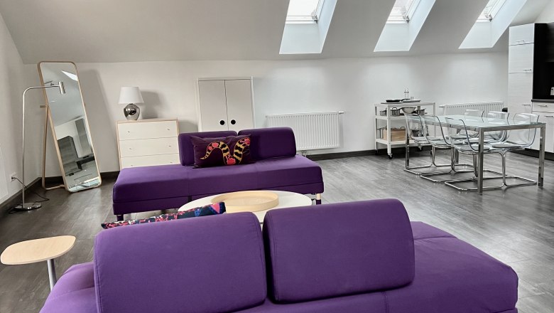 Modern loft with purple sofas, dining table and skylights.