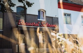 Facade of the Schrems brewery with red illuminated sign.