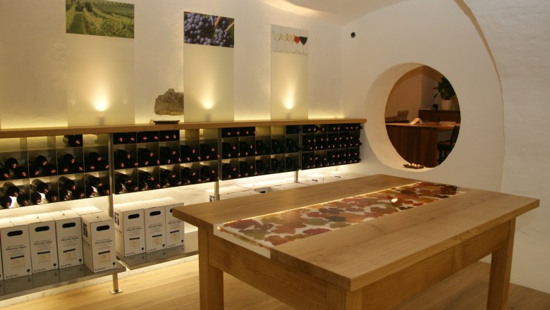 Wine cellar with shelves full of wine bottles and a wooden table in the middle.