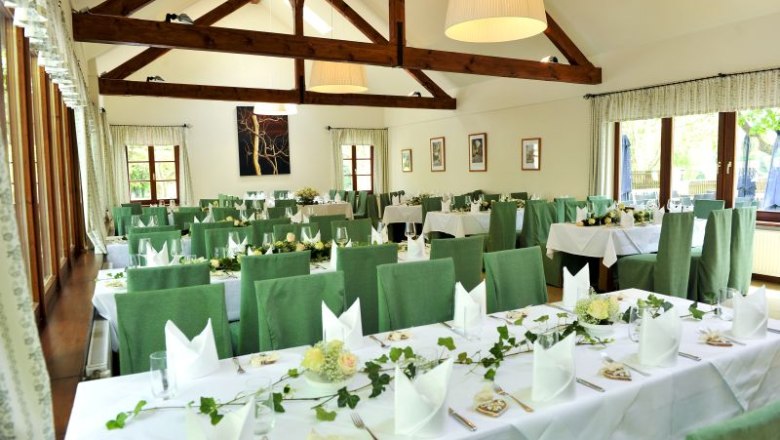 Interior view of a festively decorated inn with green chairs and wooden beams.