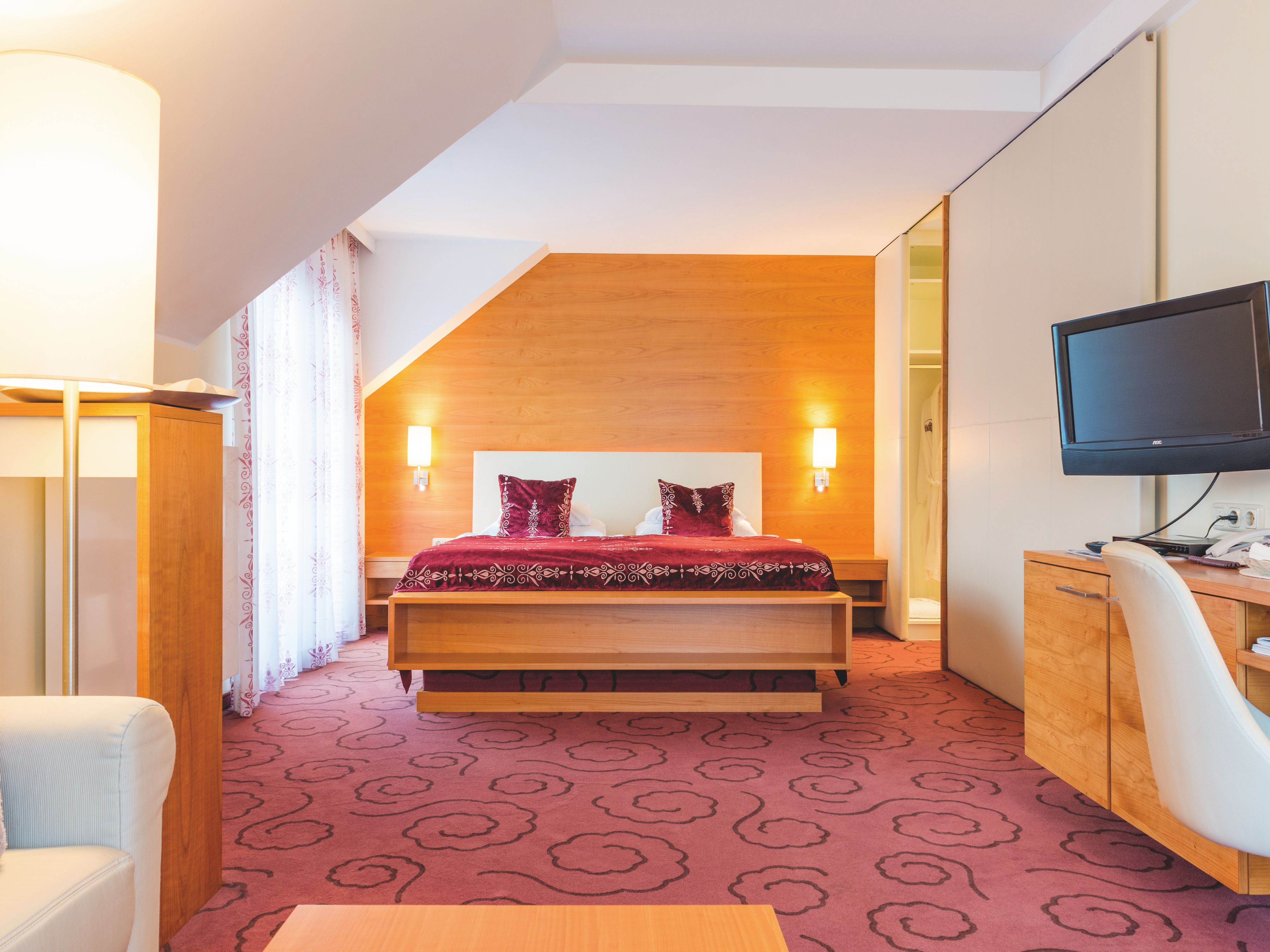 Suite with a large bed, carpeted floors, and wooden furniture.