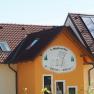Building with sign '1. Waldviertler Kinderbauernhof', solar panels on the roof.