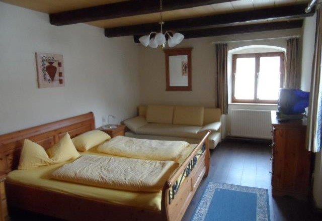 Cozy double room with wooden bed, sofa and window.