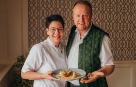A man and a woman are smiling and holding a plate of food.