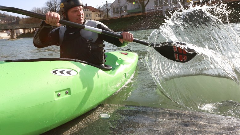 Person in green kayak paddling on a river.