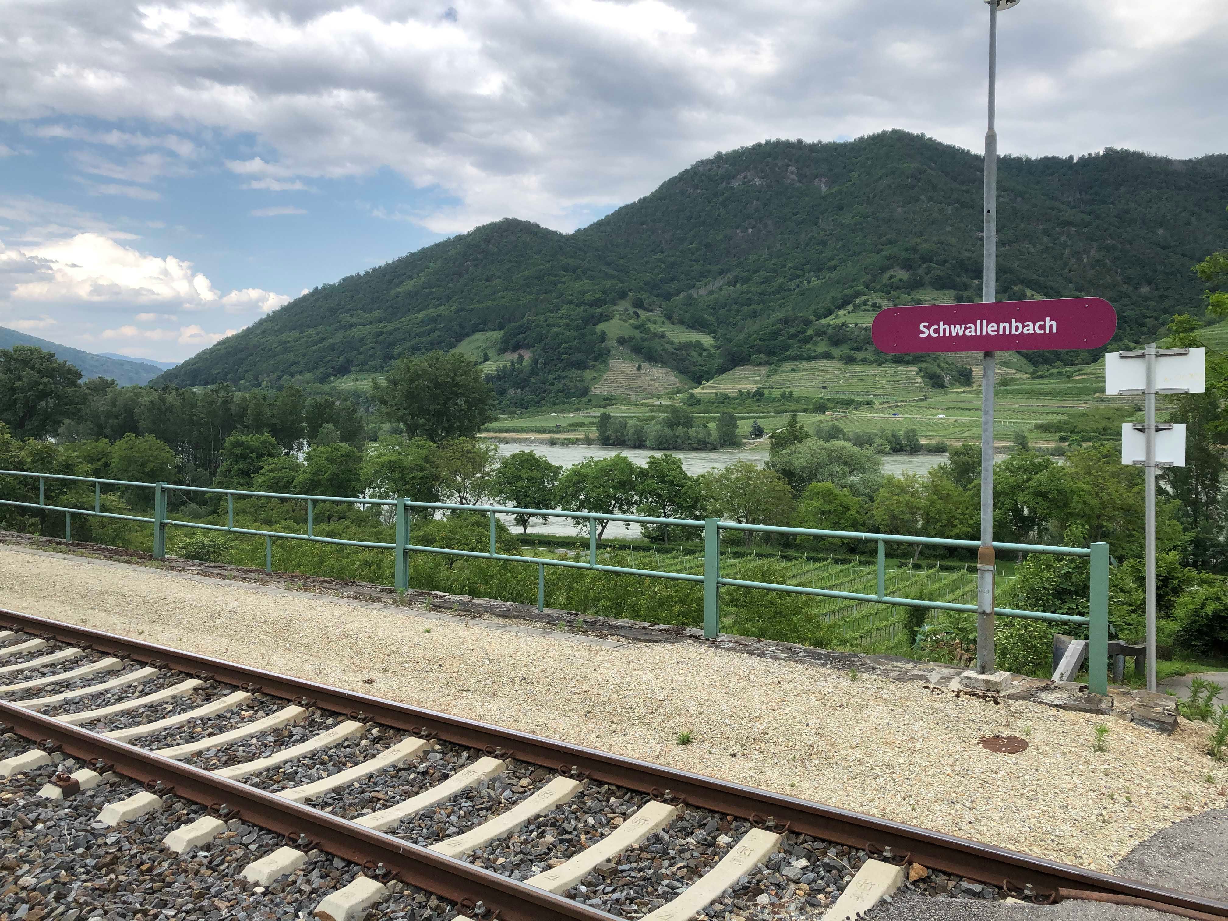 Schwallenbach station with tracks, green hills in the background.
