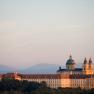 Melk Abbey in Austria at sunset with mountains in the background.