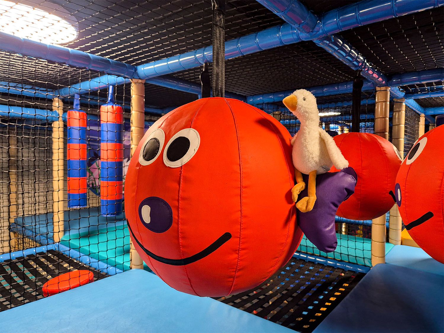 Play area with large red balls and a soft toy in an indoor playground.