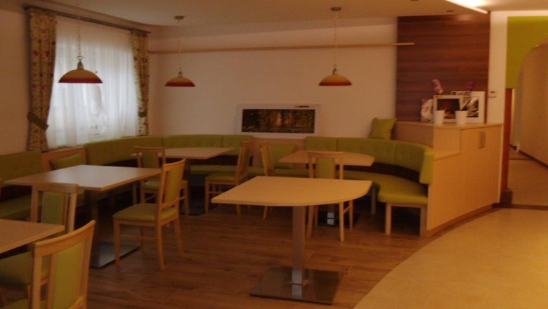 Interior view of a café with green benches and wooden tables.