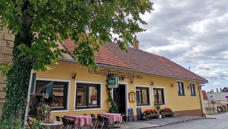 Exterior view of a traditional inn with a yellow fa&ccedil;ade and red roof tiles.