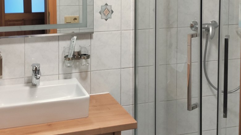 Modern bathroom with shower, washbasin and mirror.