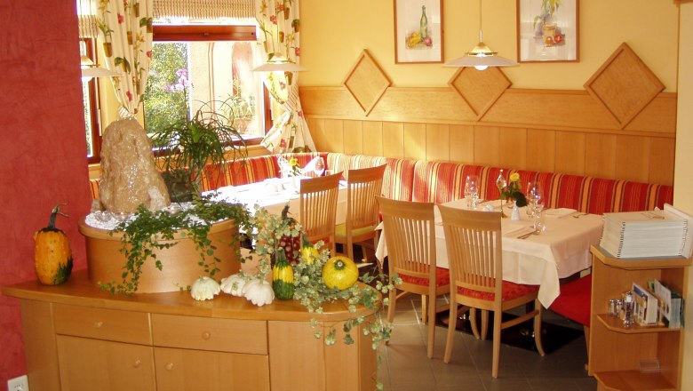 Cozy restaurant with wooden furniture, decorated with pumpkins and plants.