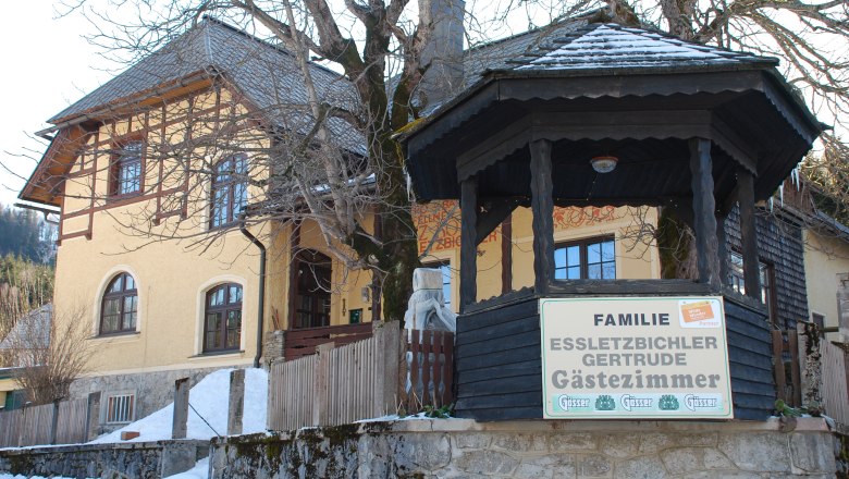 Essletzbichler, © NÖ-BBG Yellow guest house with wooden veranda and sign 'Familie Essletzbichler Gertrude Gästezimmer'.
