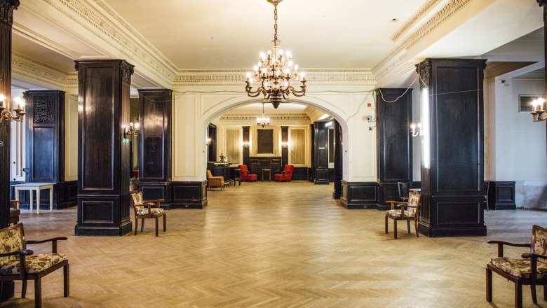 Elegant room with chandeliers and wooden furniture in the Südbahnhotel Café.
