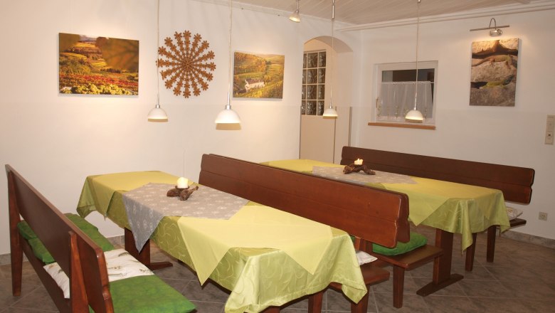 A cozy breakfast room with wooden benches, green tablecloths and wall decorations.