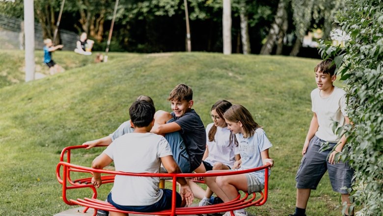 Children playing on an outdoor carousel.