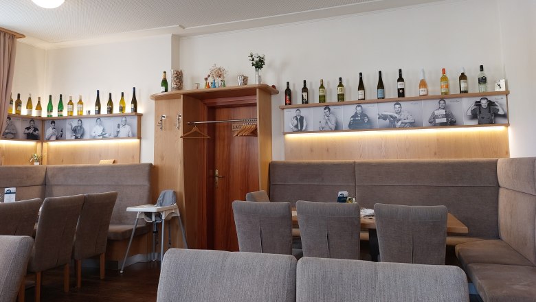 Interior view of a restaurant with wine bottles and black and white photos on the wall.