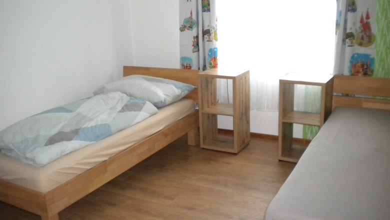 Bedroom with two separate beds and window behind it