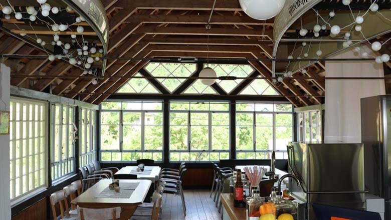 Interior view of a bright room with a wooden roof and large windows.