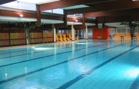 Interior view of a swimming pool with empty deckchairs at the edge of the pool.