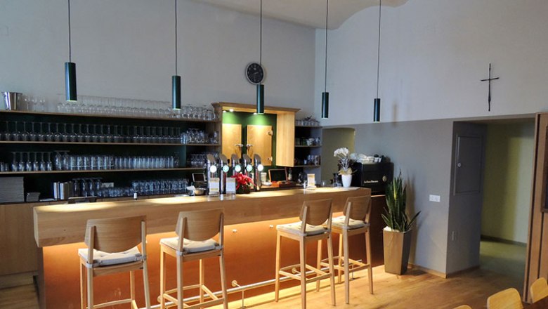 Interior view of a bar with wooden counter and bar stools.
