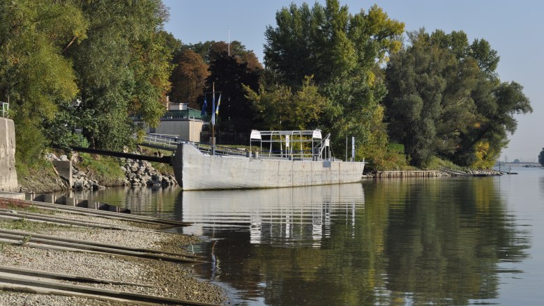 Boat landing stage on a river with trees in the background.