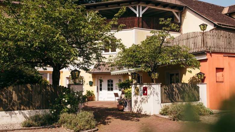 Entrance to an inn with trees and wooden fence.