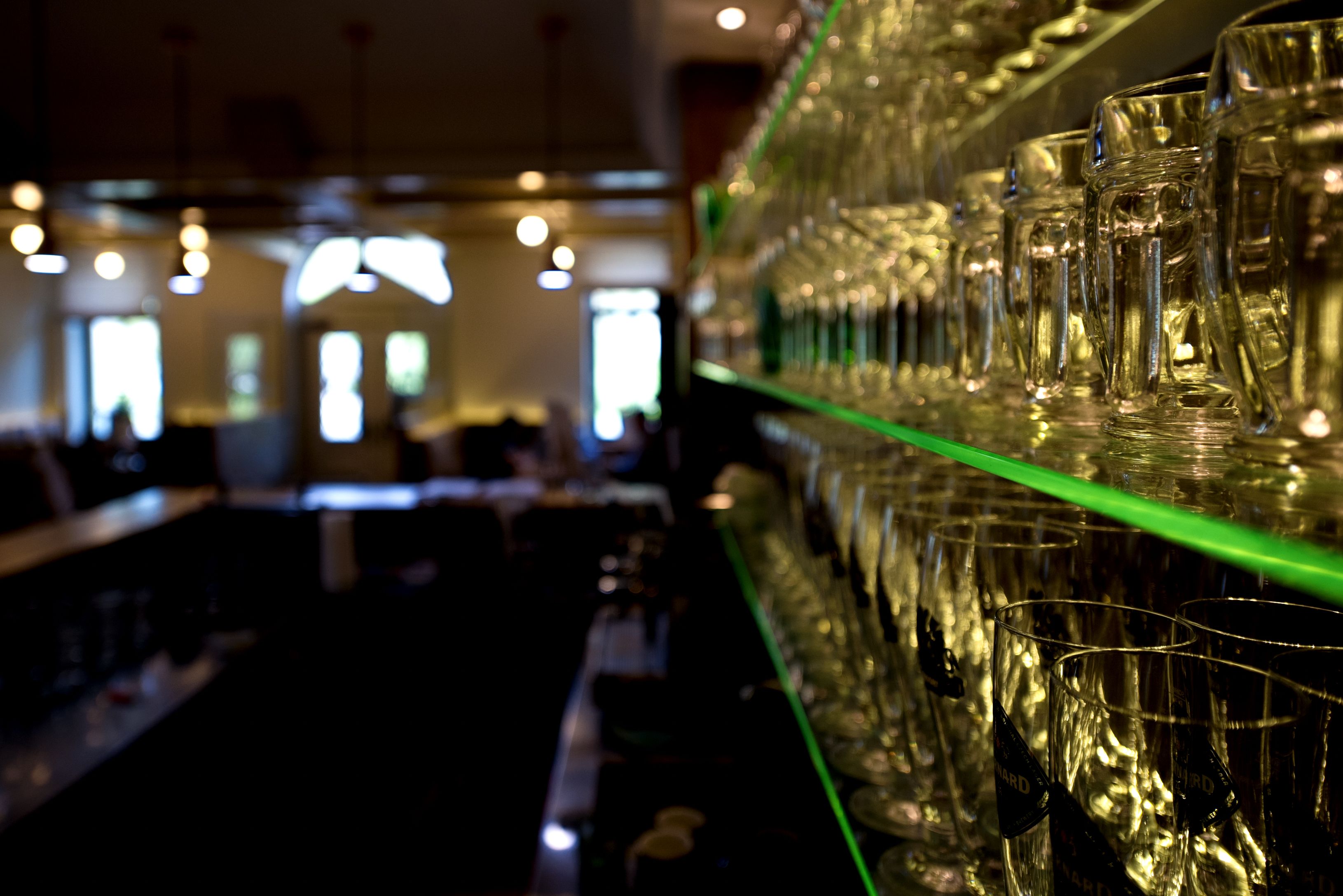 Shelf with glasses in a restaurant, blurred background.
