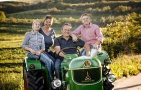 Family on a green tractor in a rural setting.