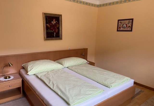 A cozy double room with a double bed, green bed linen and two pictures on the wall.