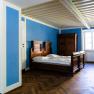 A room with blue walls, a wooden bed and a wardrobe.