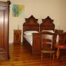 A traditionally furnished bedroom with antique wooden furniture, including two beds, a wardrobe and a table.