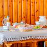 Breakfast table with crockery, bread, fruit and drinks in front of wood paneling.