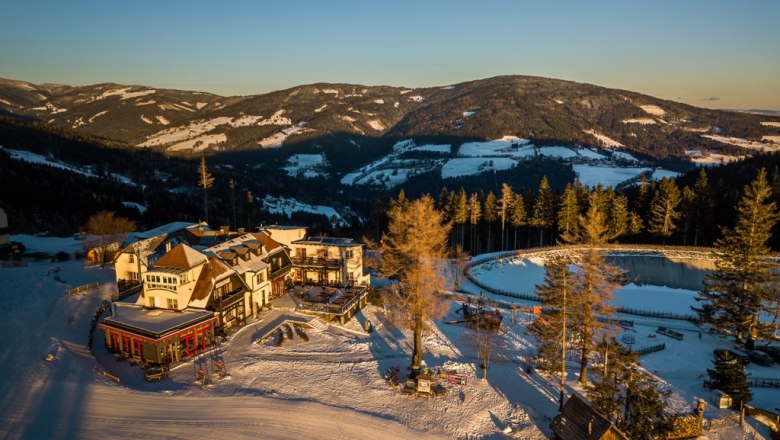 Alpengasthof Enzian in a snowy mountain landscape at sunset.