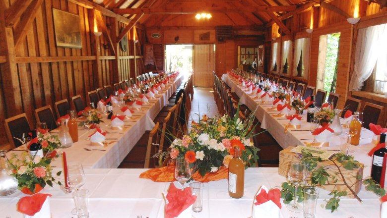 Interior view of a festively decorated hall with long tables and wooden ceiling.
