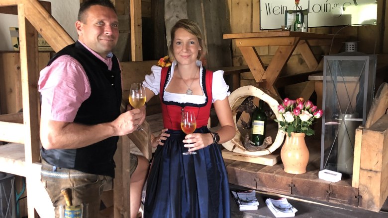 Two people in traditional dress at a wine tavern, with wine glasses in their hands.