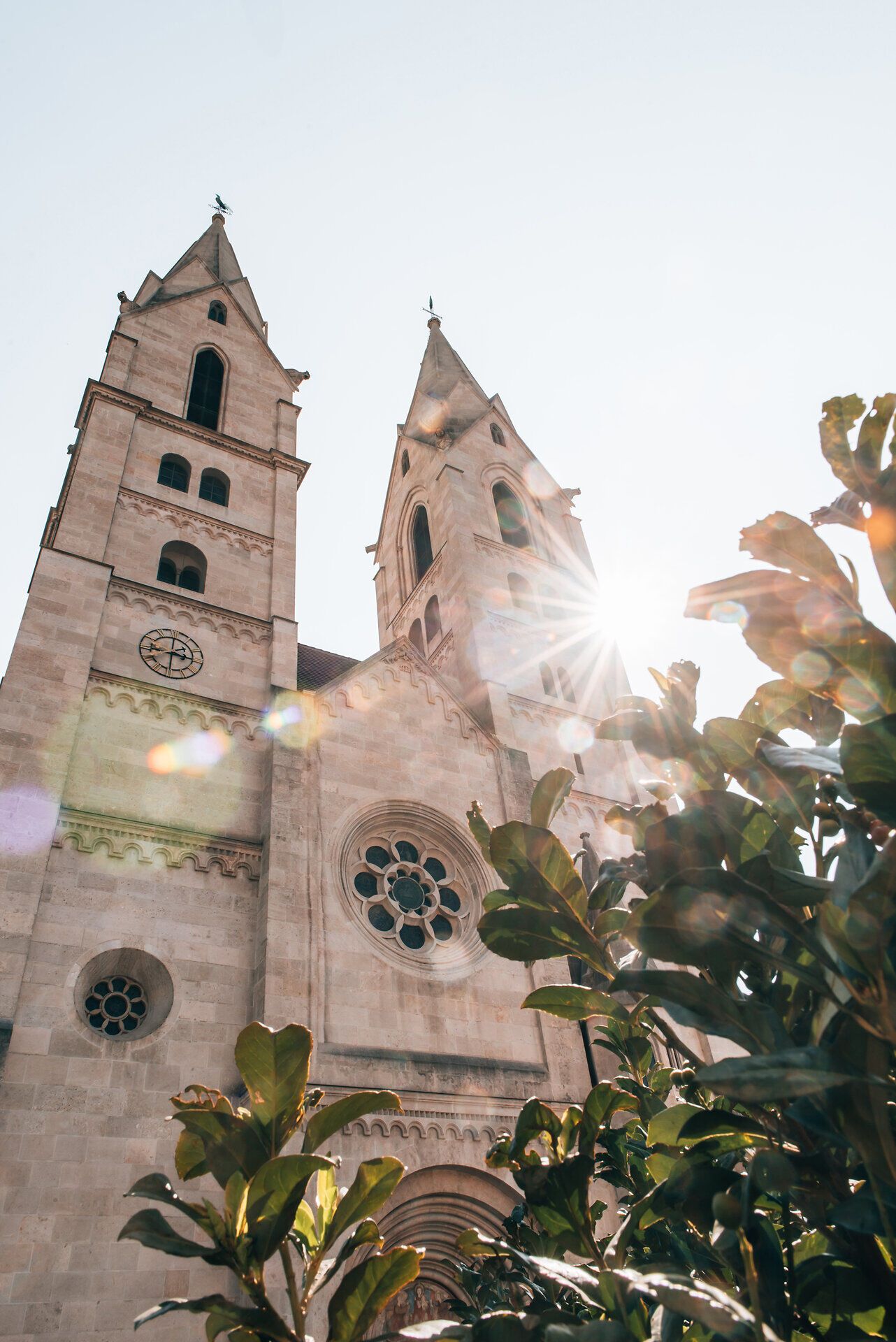 Die majestätischen Türme der Kirche ragen in den strahlend blauen Himmel und fangen das Licht der Sonne ein. Umgeben von üppigem Grün, strahlt dieser Ort eine friedliche Atmosphäre aus, die zum Verweilen einlädt. Hier vereinen sich Geschichte und Natur in harmonischer Weise.